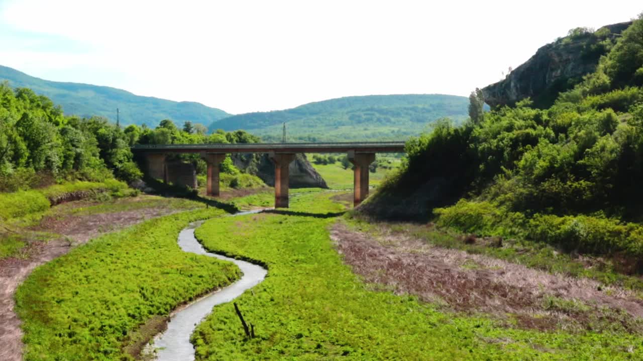 A bridge above a river in the summertime