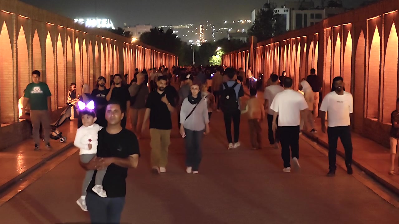 Folla di persone che cammina lungo un ponte storico illuminato di notte