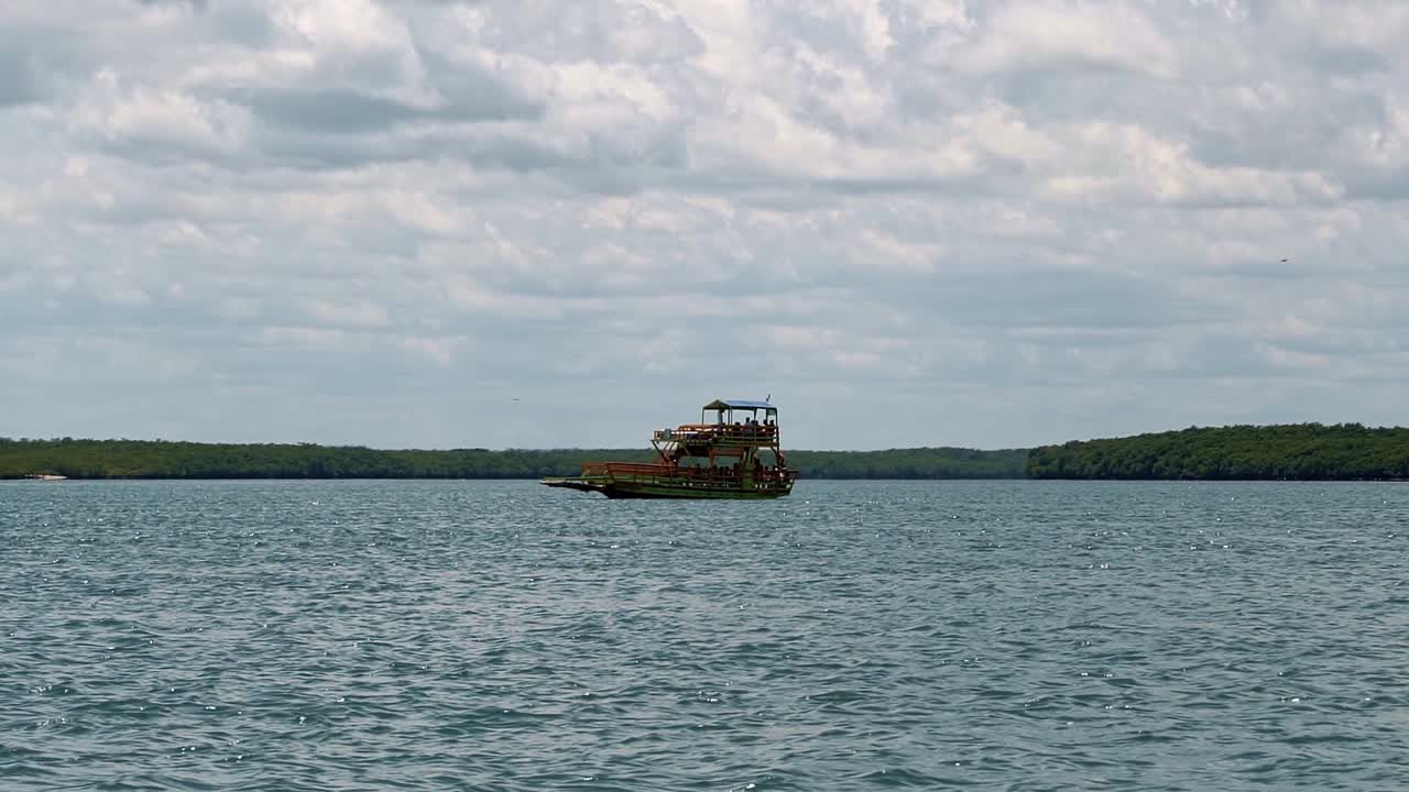 toma en cámara lenta de un barco de transporte turístico que navega hacia la playa de restinga en un gran río de movimiento lento cerca de la ciudad costera de barra do cunhaú en rio grande do norte, brasil en un día de verano