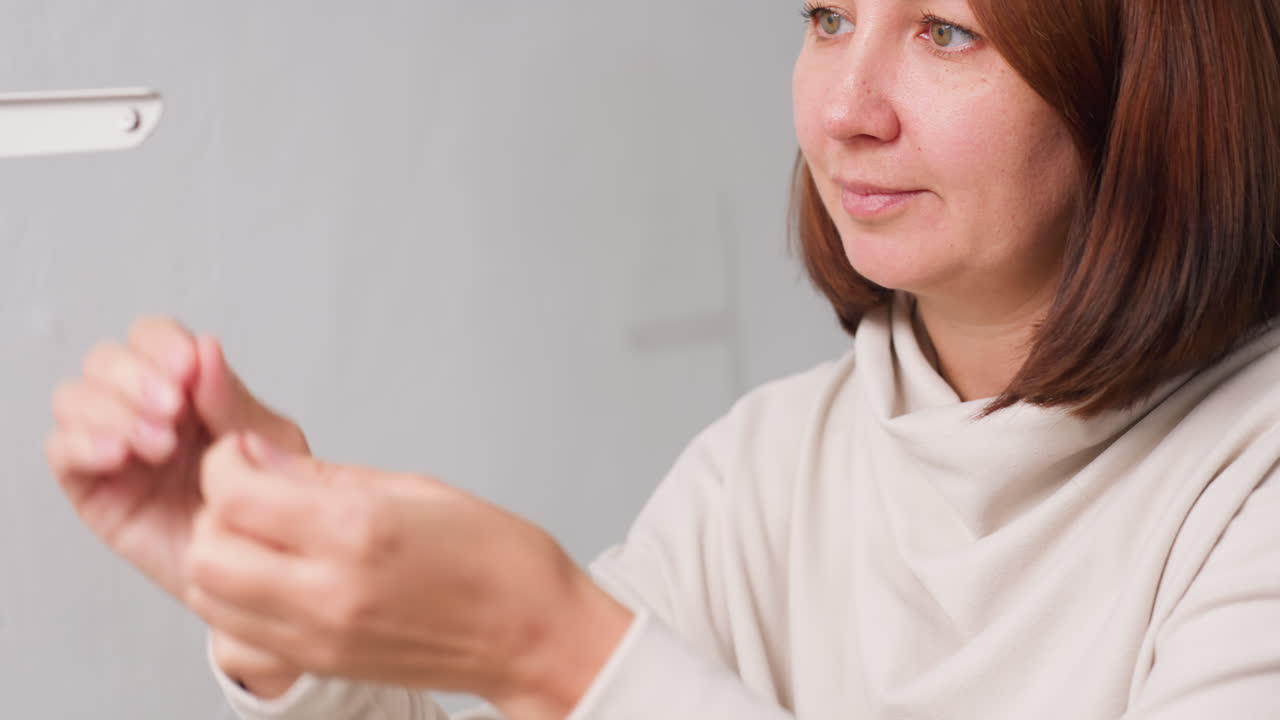 Focused creative individual carefully guiding white thread into hole on sewing machine, displaying precise technique, concentrated facial expression, and expert craftsmanship in cozy sewing workspace