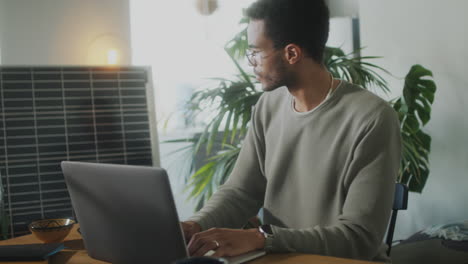 man charging laptop with solar panel in home office
