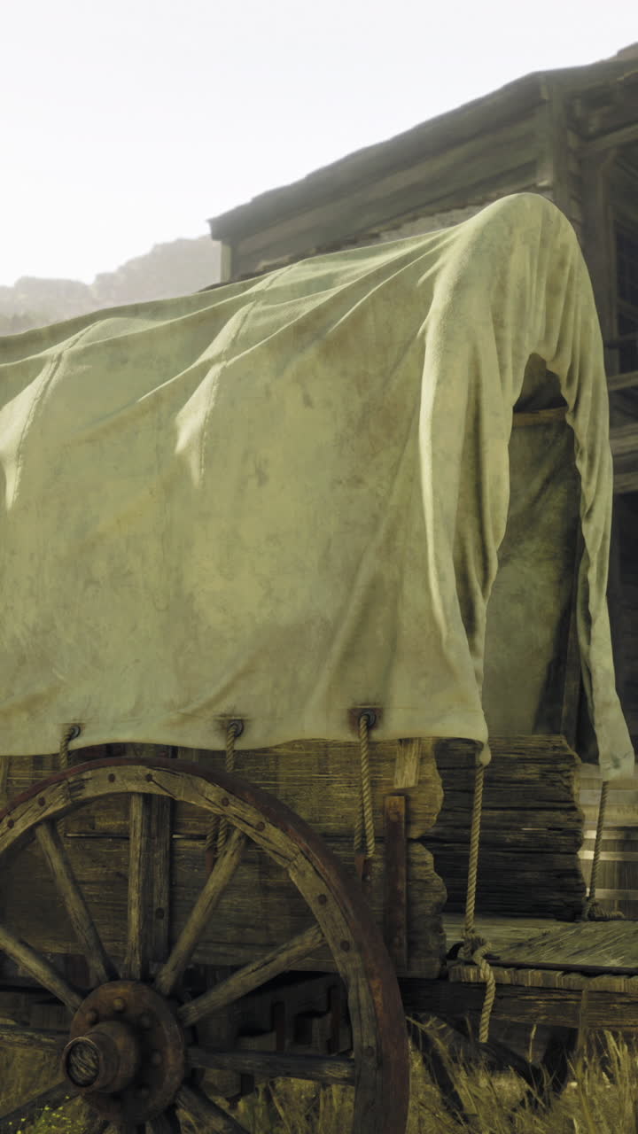 Old wooden wagon with a cloth cover beside a rustic wooden building