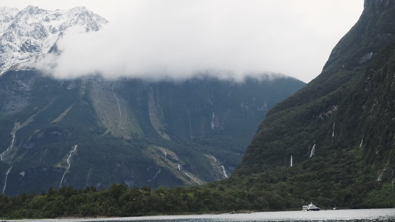 뉴질랜드 의 밀포드 사운드 의 거대한 절벽  ⁇  에 작은 배 가 나타납니다.
