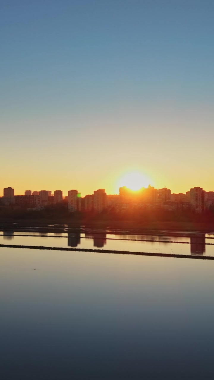 Sunrise over city skyline near water in salt industry setting
