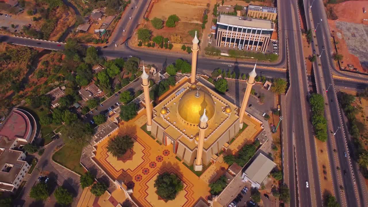 High angle aerial of the Abuja National Mosque with a golden dome and tall minarets at the corners of the building