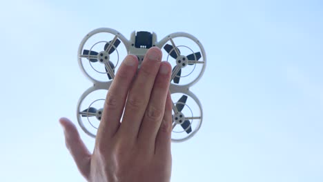 neo quadcopter drone flying off from palm of hand, low angle view