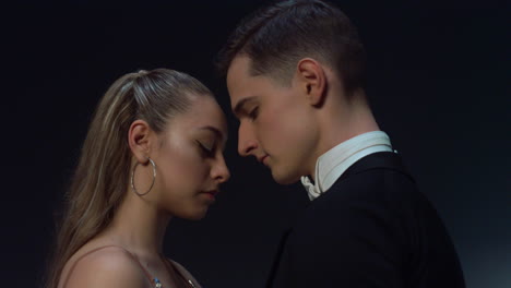 Ballroom-couple-standing-in-dark-background.-Young-dancers-looking-each-other.