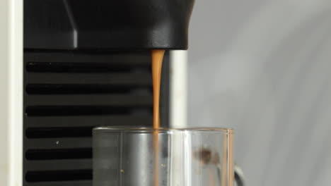 café recién preparado goteando de la máquina de café en una taza de vidrio