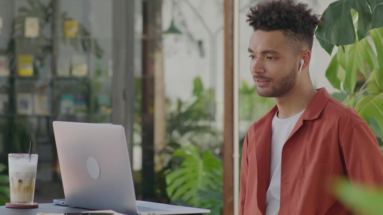 Man Video Calling on Laptop and Drinking Coffee in Outdoor Cafe