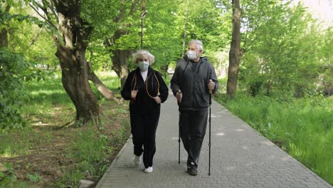 active senior old man, woman training nordic walking in park during quarantine