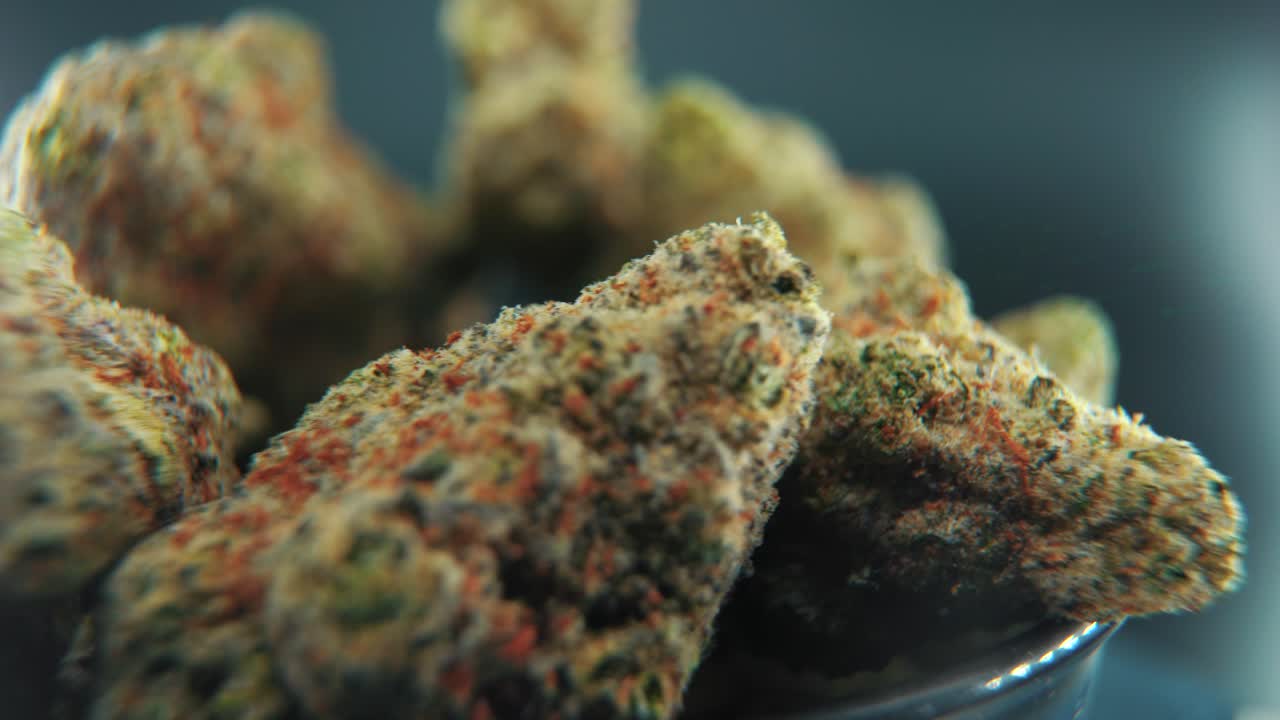 A macro cinematic detailed shot of a cannabis plant, hybrid strains, Indica and sativa ,marijuana flower, on a 360 rotating stand, black shiny bawl, slow motion, 4K video, studio lighting