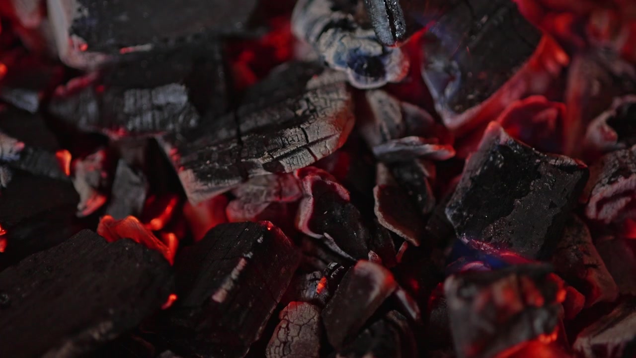 Close-up of Red Hot Glowing Charcoal Embers with Small Blue Flames