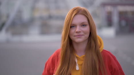 young pretty red haired woman smiling and walking towards the camera outdoors