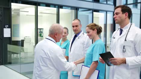 Doctor-shaking-hands-and-interacting-with-colleagues-in-corridor