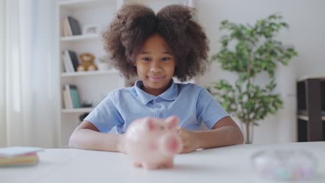 una niña emocionada poniendo monedas en la alcancía, ahorrando para algo especial