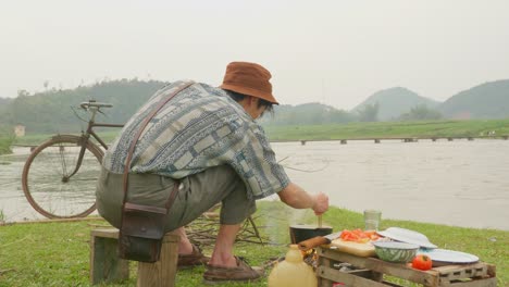 close up of man cooking food outdoor near the lake