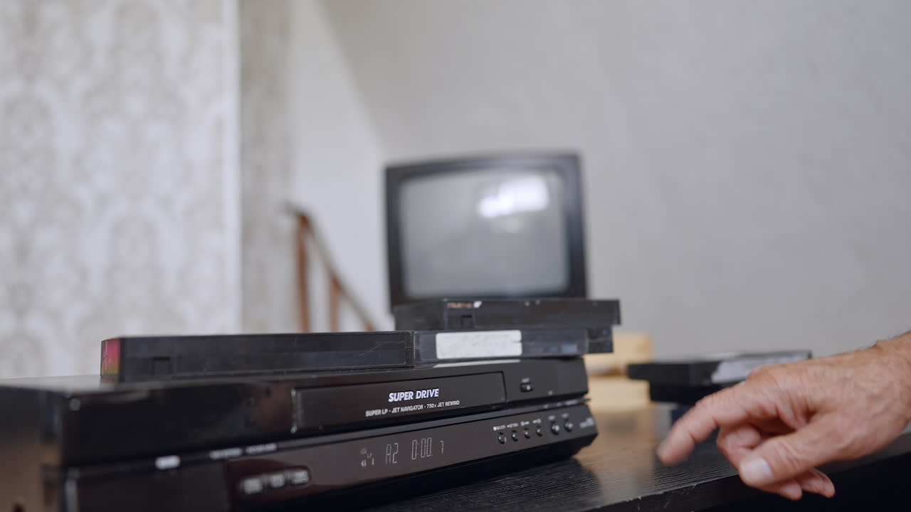 Old-style VHS player on the desk. Male hand presses the button on the device. Close up