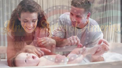 animation of flag of usa waving over happy caucasian parents playing with baby