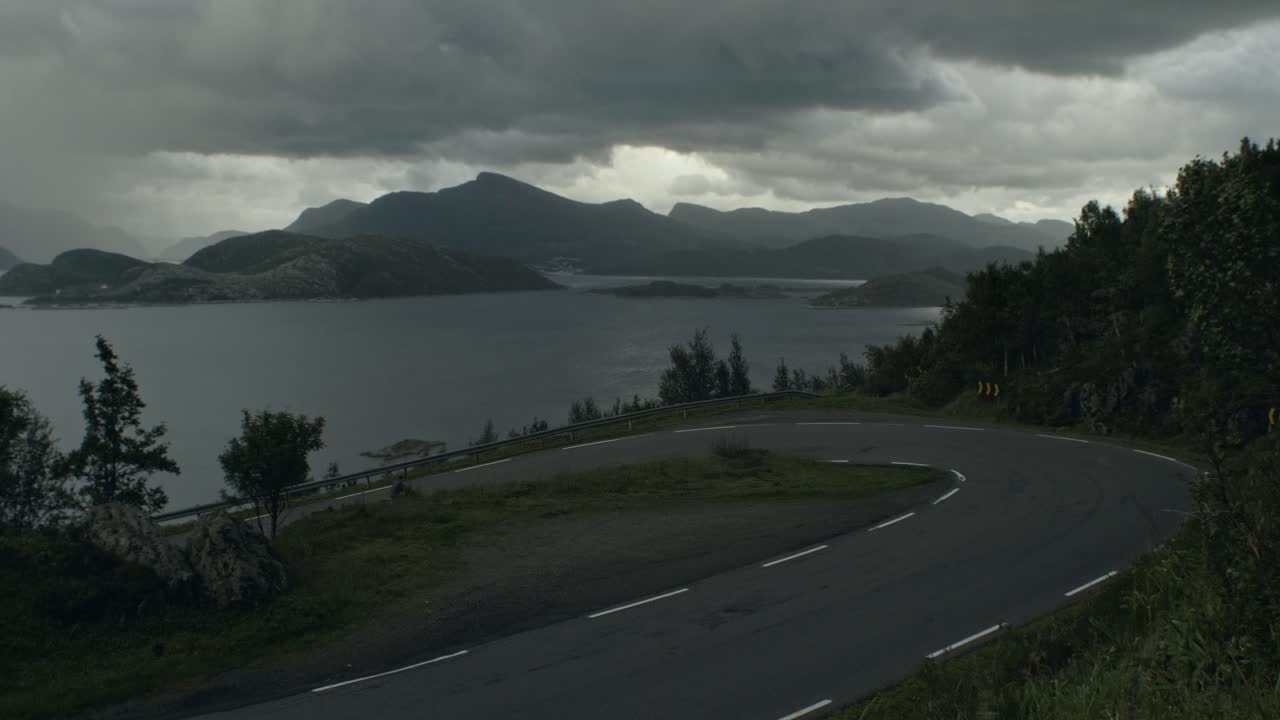 어둡고 변덕스럽고 바람이 많이 부는 날씨, 폭풍 양조, 완전히 포장된 여행용 자전거를 타고 오르막을 오르는 청년