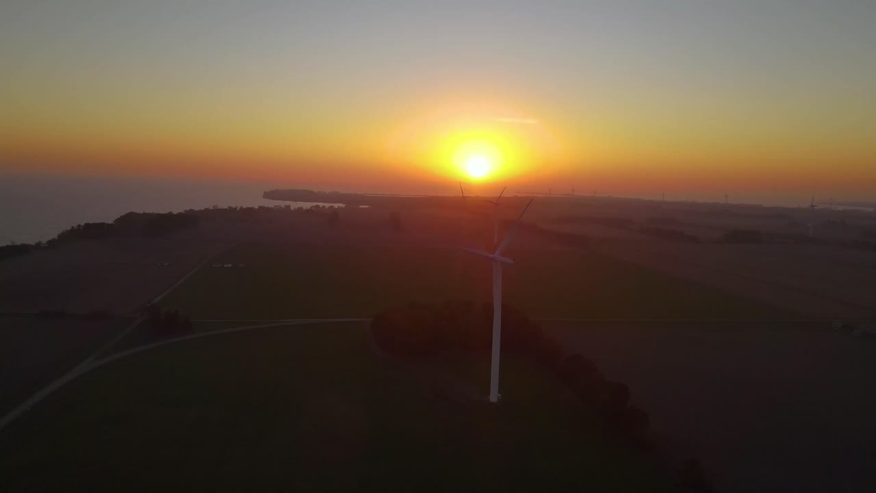 Drone aerial view of wind energy generator power plant with yellow sun background