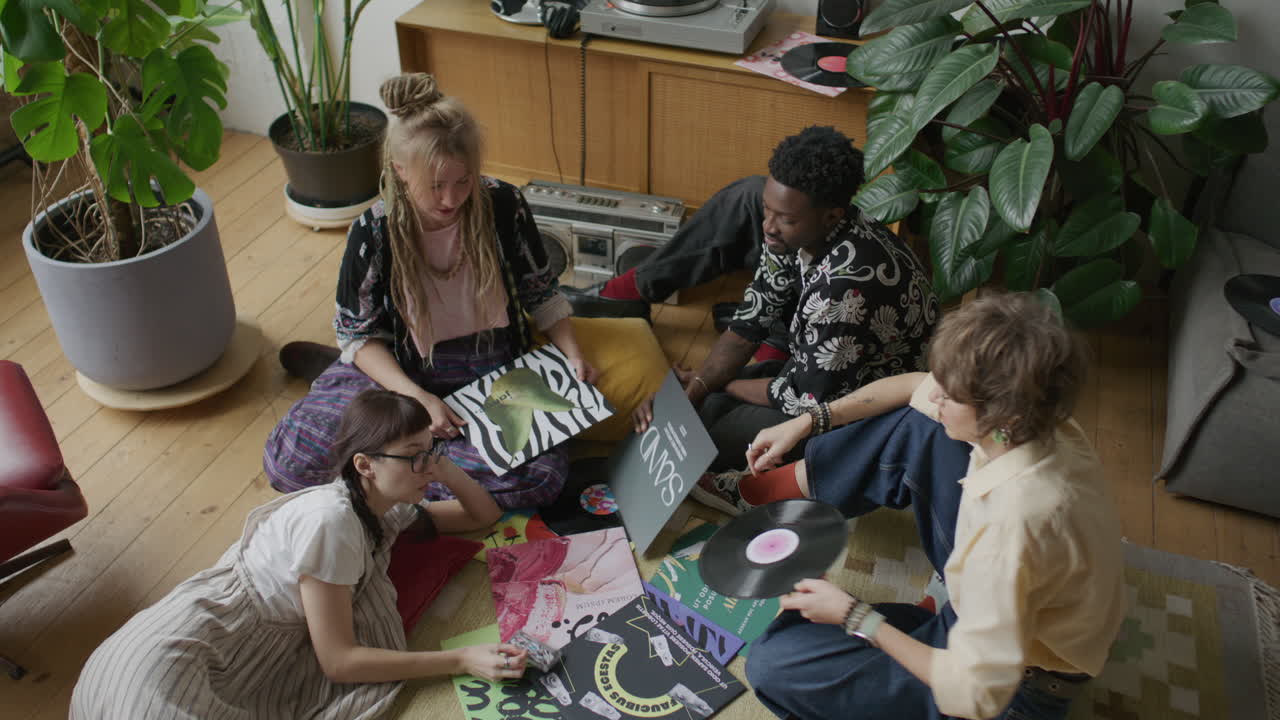 Gruppe unge venner diskuterer vinylpladesamling på gulvet derhjemme