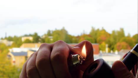 lighting up a dark black pipe with a tobacco inside to enjoy the moment of silence and peace with modern gas lighter to taste the goodness of the earth and relax from everyone cinematic view