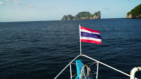 the flag of thailand flies on the bow of a diving vessel near pih leh lagoon off koh phi phi island, thailand