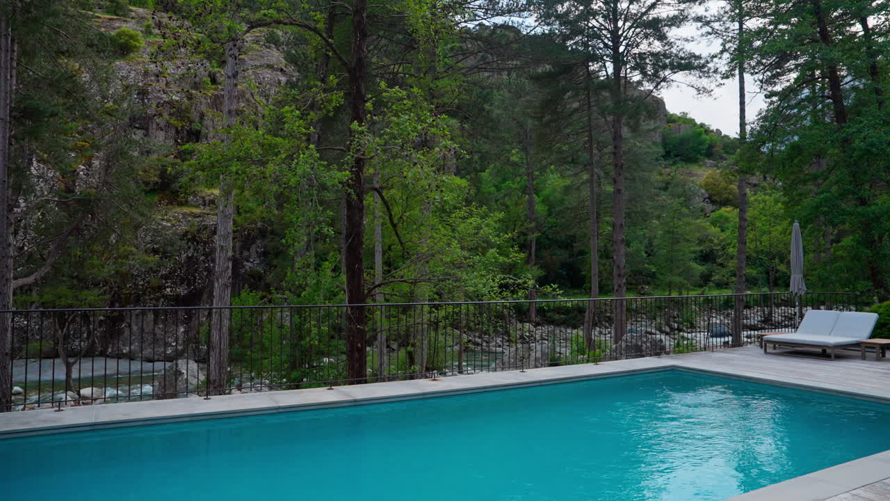 Udendørs pool i et resort i skoven omgivet af bjerge