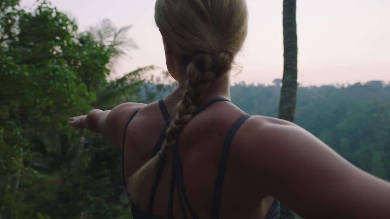 mujer de yoga practicando pose de guerrero al aire libre al amanecer disfrutando del ejercicio de atención plena 4k