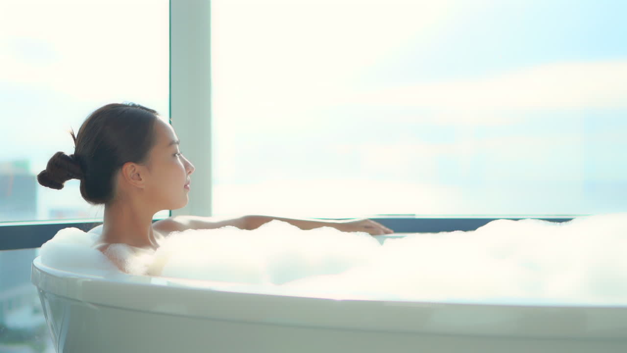 아름다운 젊은 여성이 거품 목욕을 하며 휴식을 취합니다.