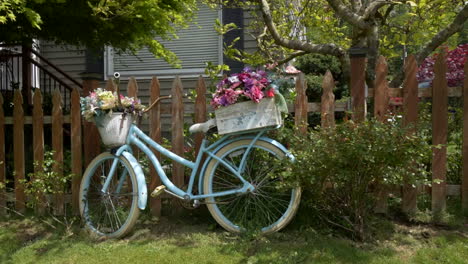 bicycle planter with flowers along picket fence with trees and shrubs