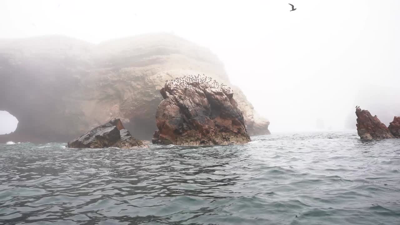fotografía cinematográfica de la formación de enormes rocas en tiempo de niebla en el océano pacífico en la reserva nacional de paracas, ica, perú