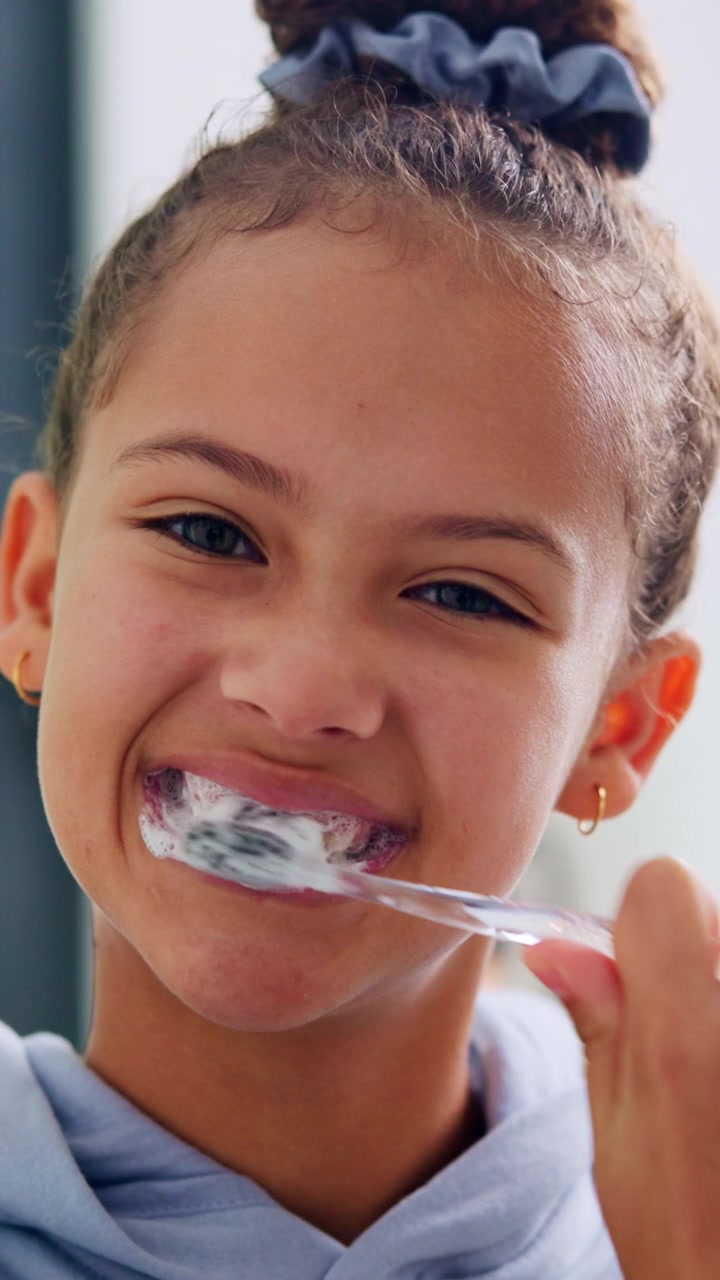 Young Girl Brushing Her Teeth with Charcoal Toothpaste