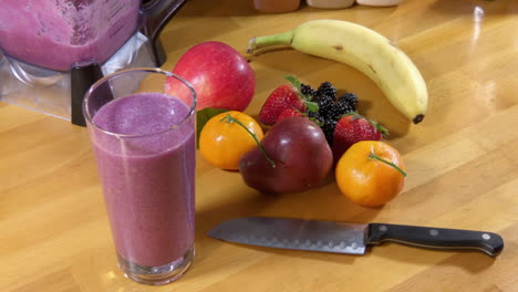 tiro de belleza, vaso lleno de batido de frutas y fruta en el mostrador de carnicero de madera