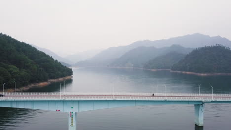 4K-Bridge-at-Qiandao-Lake,-Cyclist,-China