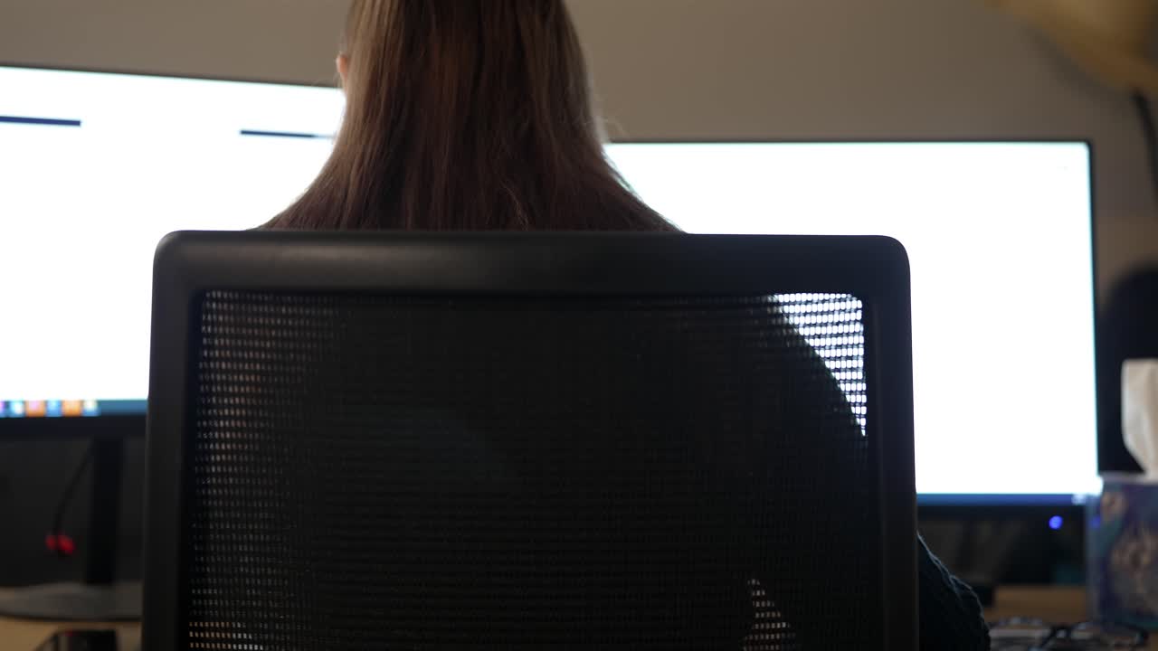Businesswoman Working on Dual Monitors in Office, Rear View
