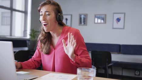 feliz mujer de negocios caucásica haciendo una llamada de video usando una computadora portátil en el escritorio, en cámara lenta