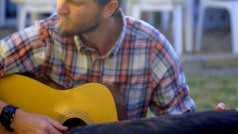 hombre con su perro tocando la guitarra en el jardín 4k