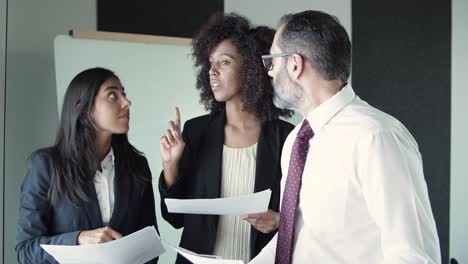 three business partners holding documents and discussing project