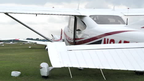 small high-wing airplane at grass airfield, performing engine startup