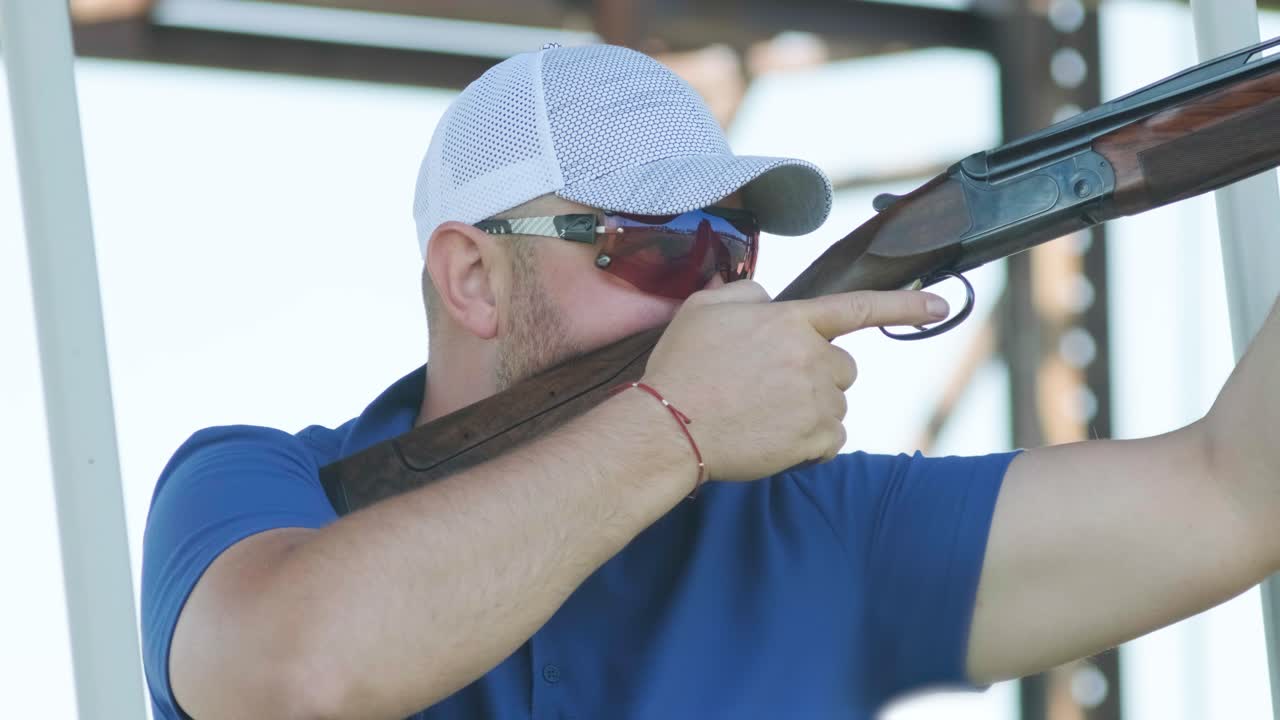 스포츠맨이 이중 배럴 건으로 총을 고, 슈팅 테스트를 위한 스포츠 경기장은 날아다니는 스케이트를 고 있습니다.
