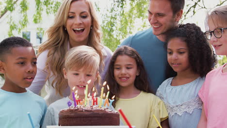 Padres-Con-Hijo-Celebrando-Cumpleaños-Con-Amigos-Haciendo-Fiesta-En-El-Jardín-Y-Apagando-Velas