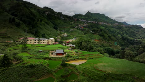 aerial high angle overview above sapa valley, with terraced fields as sunlight streams across vegetated green ridges and valleys on misty day