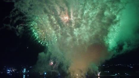 huge colorful firework in winter night sky over city illuminated by lights filmed by drone