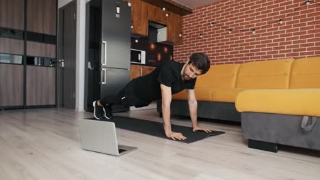 Man-athletic-trainer-doing-push-up-at-home-live-teaching-via-laptop-or-video-call