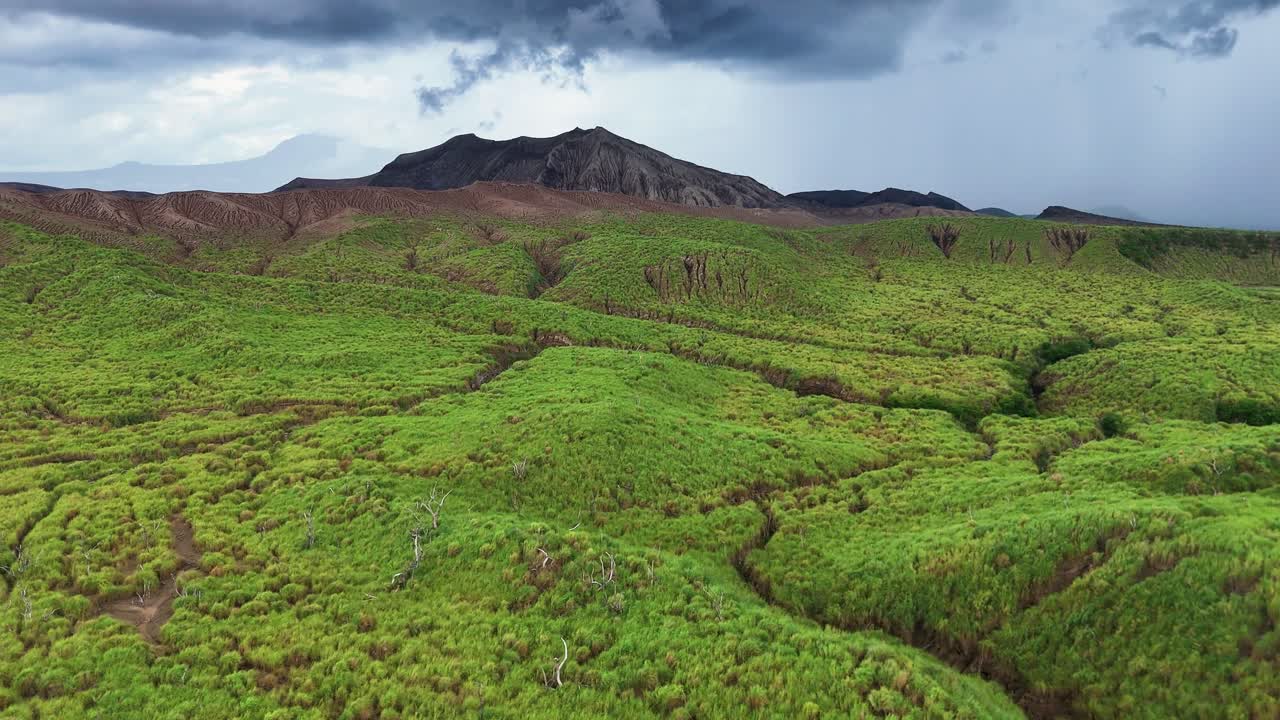 Lento sorvolo aereo sulla lussureggiante vegetazione della catena montuosa di Tagaytay nelle Filippine, che si muove verso il vulcano Taal in una giornata nuvolosa, con luce soffusa che mette in risalto il paesaggio tropicale