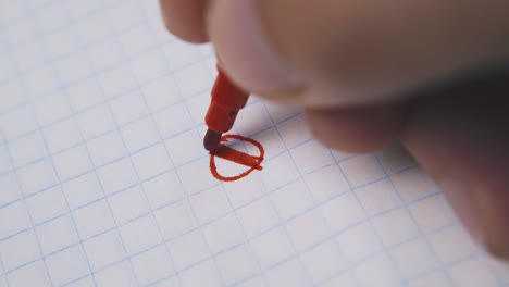 person draws circle with red marker on blank checkered paper