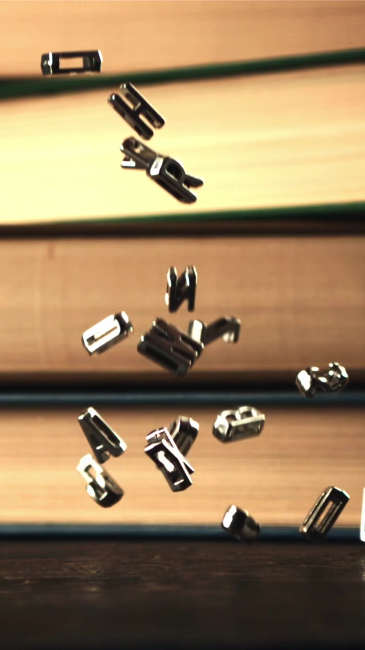 Lettere metalliche che cadono al rallentatore su uno sfondo di libri.