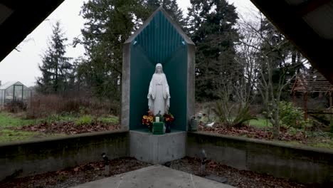 Toma-De-Zoom-De-Una-Estatua-De-La-Virgen-María-En-Un-Altar-Al-Aire-Libre-En-El-Parque-En-Un-Día-Nublado