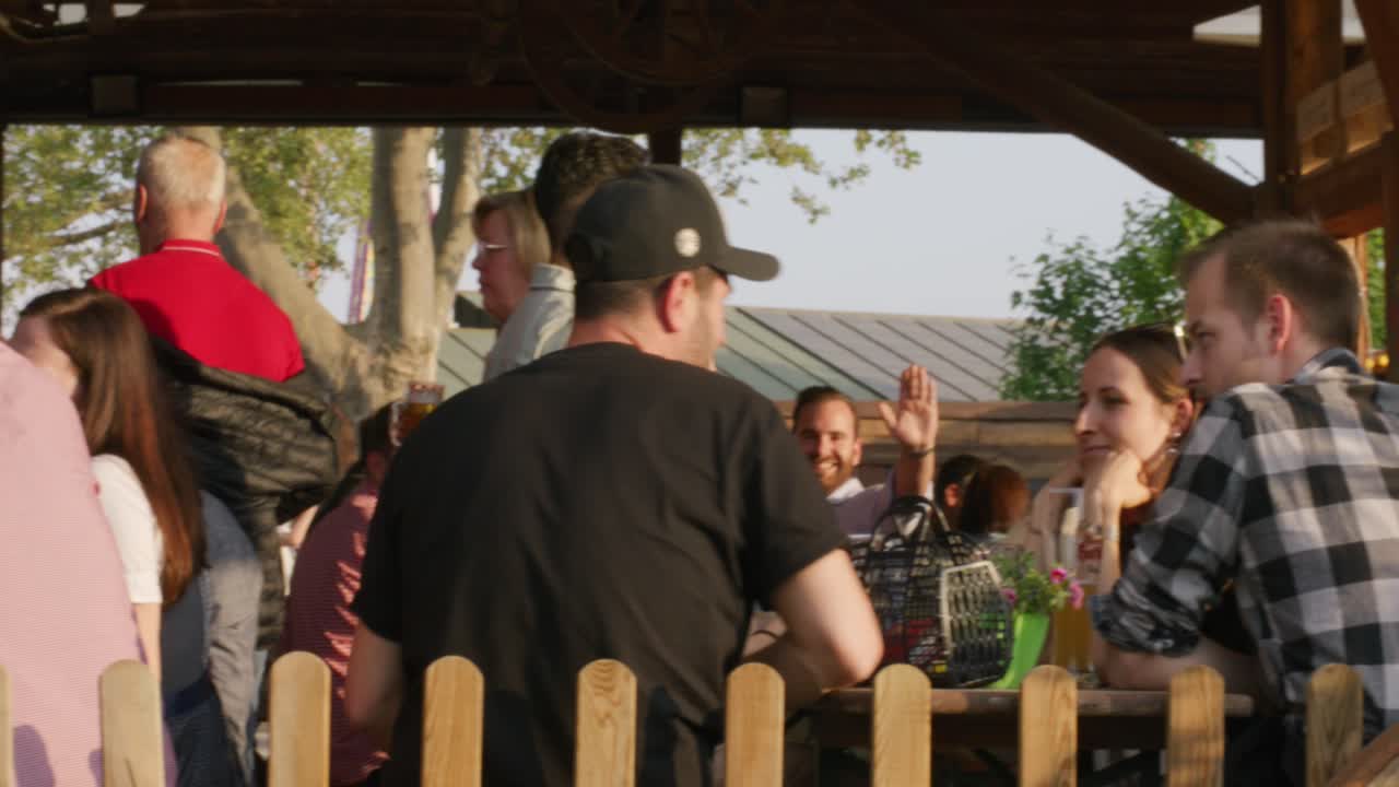 Crowd of people sitting down talking and drinking at tables at Balvarian outdoor Spring Fest in Stuttgart, Baden Wurttemberg, Germany, Europe, afternoon panning view angle